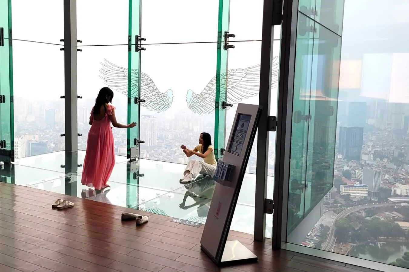Visitors on the glass-floored Sky Walk at Hanoi Sky, with the city far below