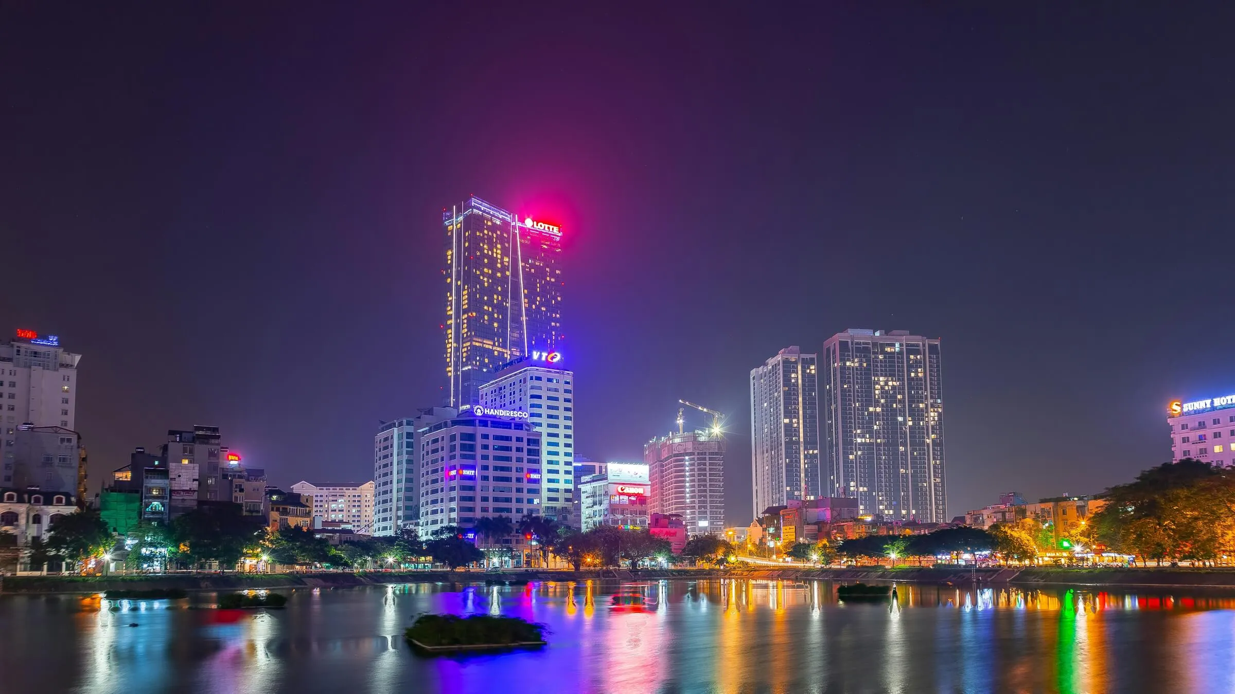Lotte Center Hanoi lit up at night above the city, reflected in a lake